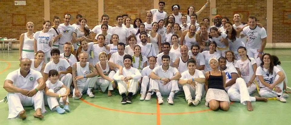 A large group of capoeiristas in white on a sports hall court at Cyproeira in Nicosia