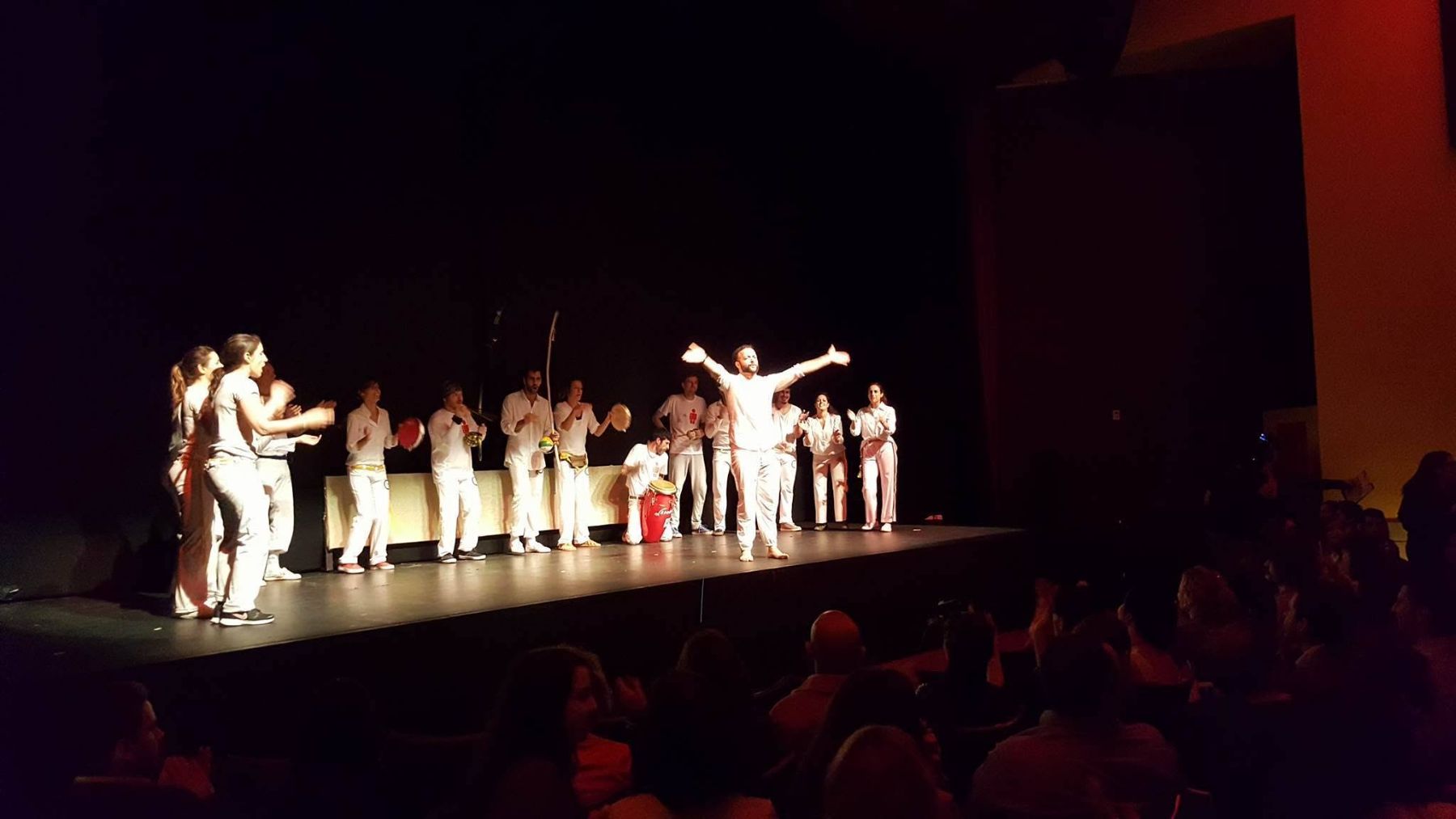 Apêiara capoeiristas in white on stage with instruments at a film festival performance in Limassol