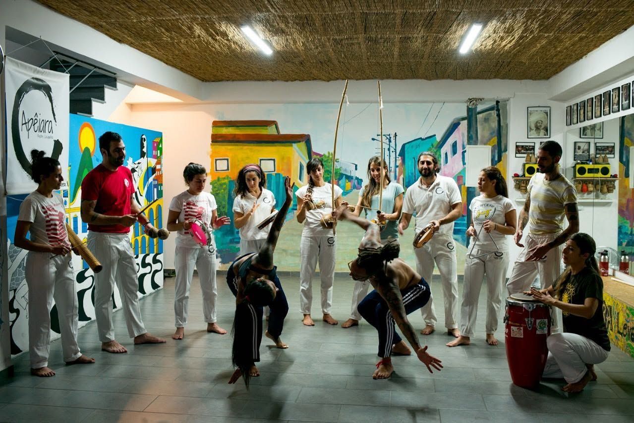 Two Apêiara students playing in the roda, with the bateria around them
